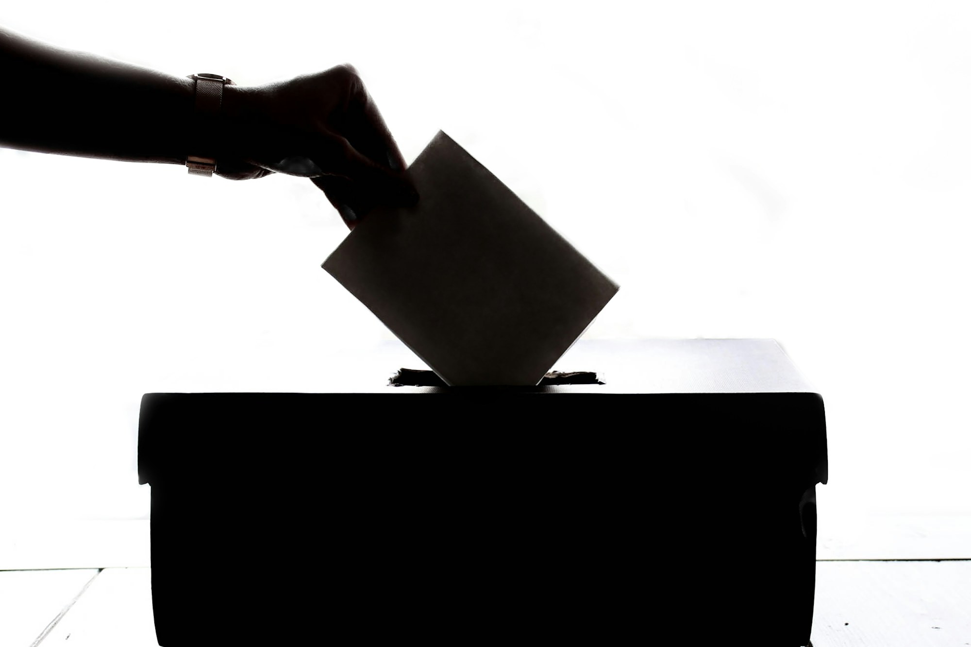 A voter placing a private paper ballot into a ballot box as a visual metaphor for secret online voting